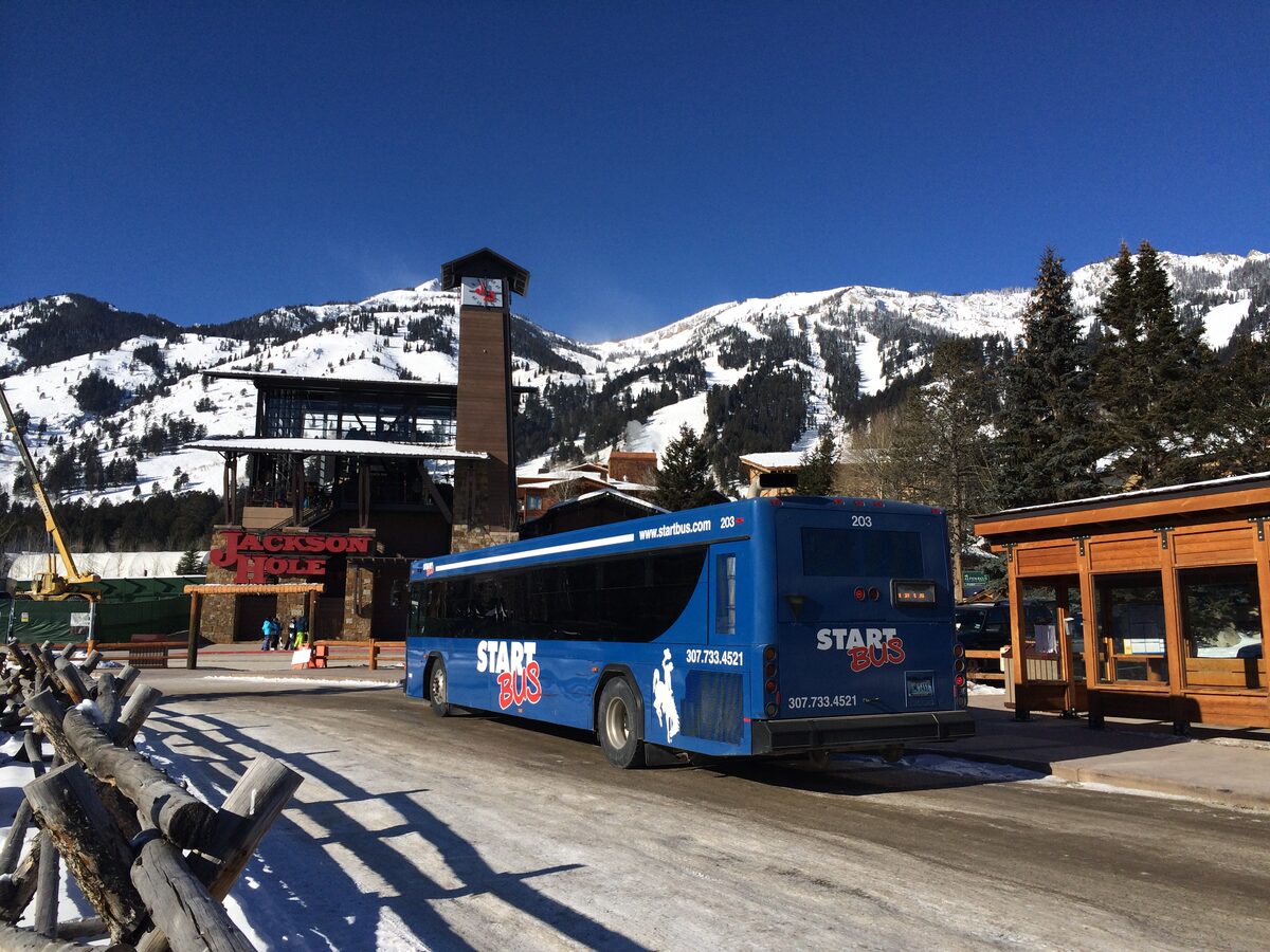 A blue START bus parked in snowy Teton Village, with the mountains behind it