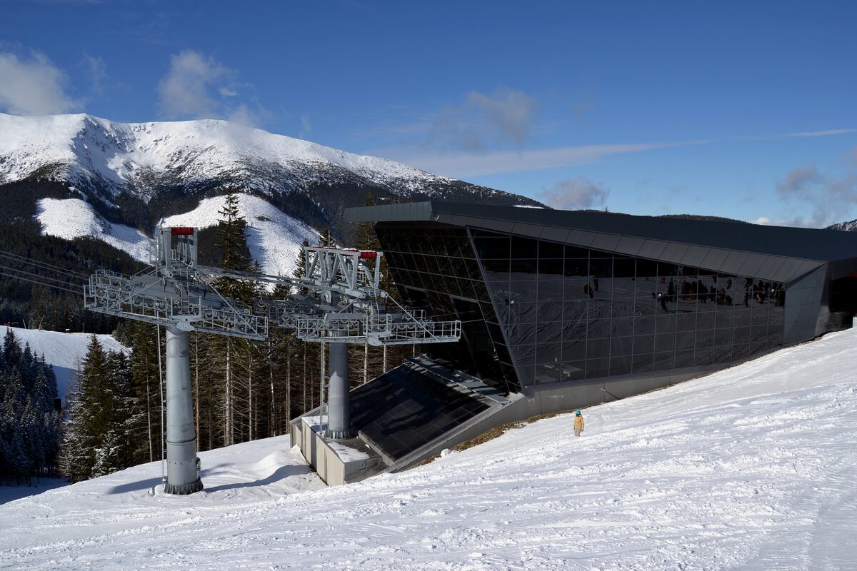 A dark modern gondola station with lift pylons standing in deep snow