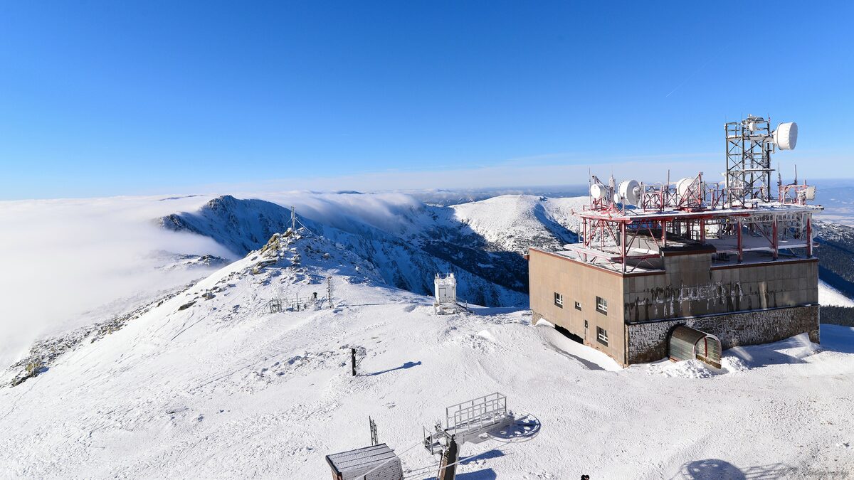 The snowy Chopok summit with its station building and antennas above a sea of cloud