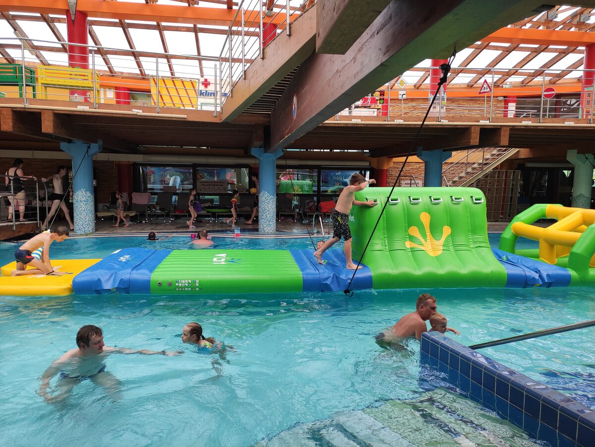 Swimmers in the indoor pool hall at Tatralandia, with an inflatable obstacle course on the water