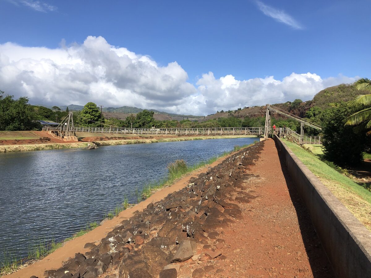 Hanapēpē Swinging Bridge crossing the river under blue sky