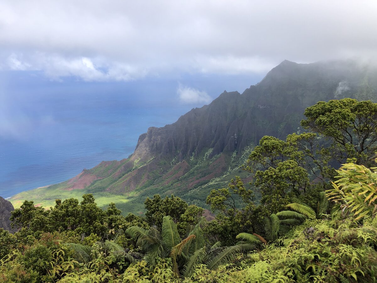Cloud-draped green ridges of Kalalau Valley meeting the blue sea