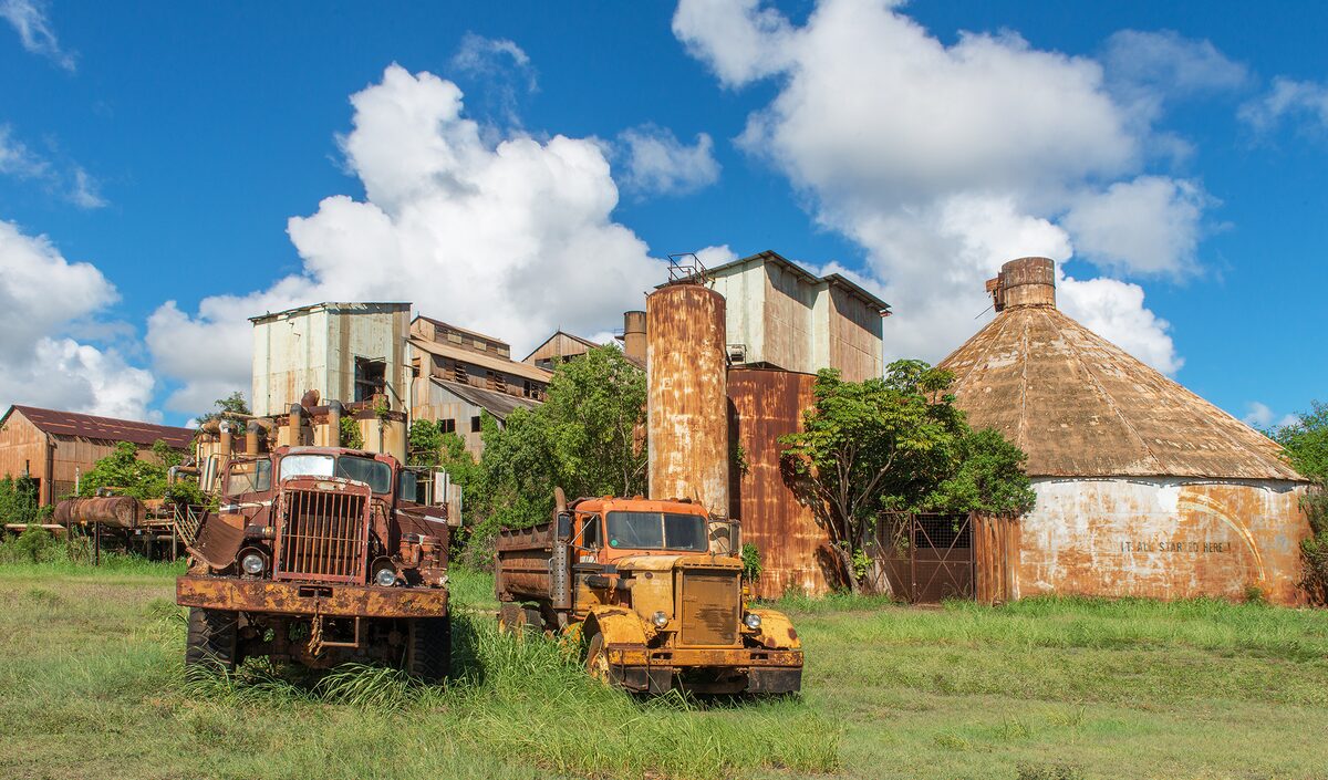 Old Kōloa sugar mill with rusting work trucks in front
