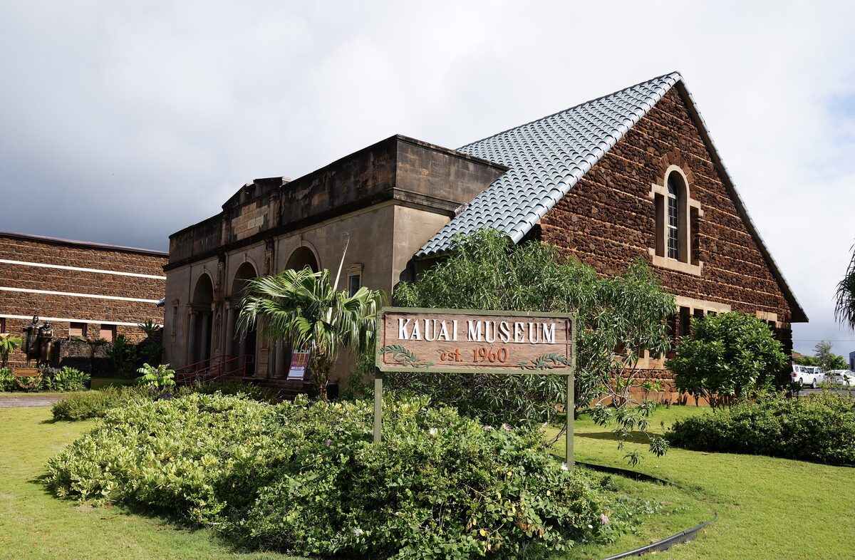 Brick and stone Kauaʻi Museum building behind a green lawn