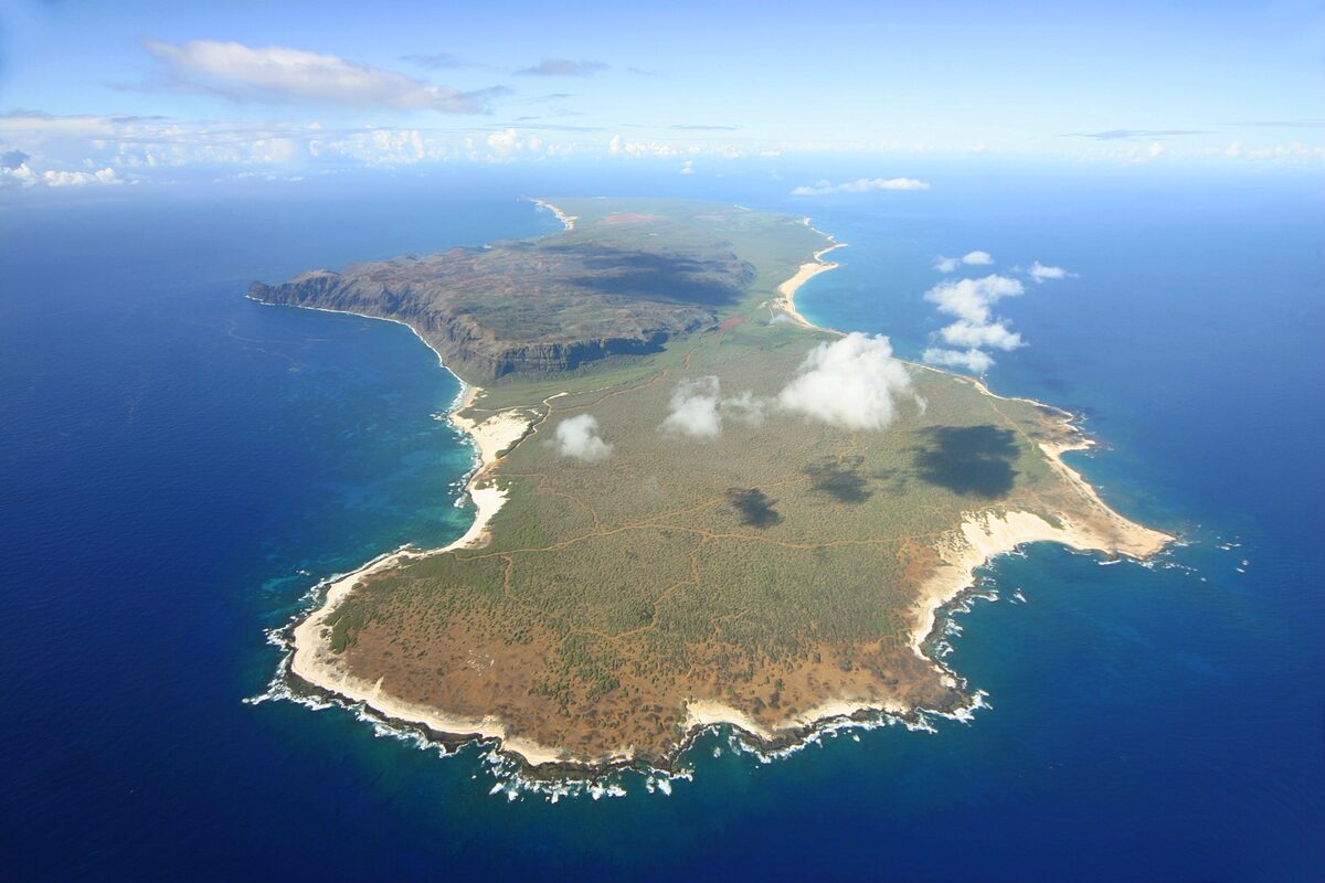 Aerial view of Niʻihau ringed by white surf and blue sea