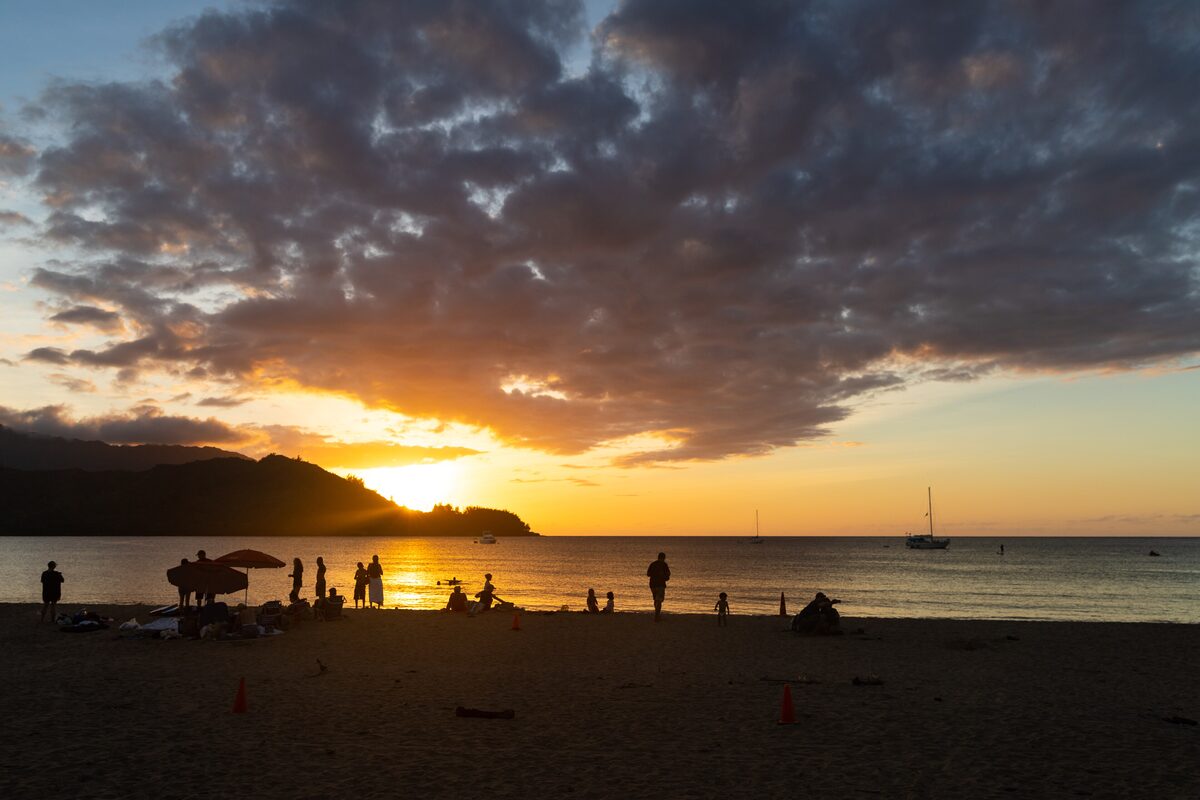 Sun setting behind the headland over Hanalei Bay beach