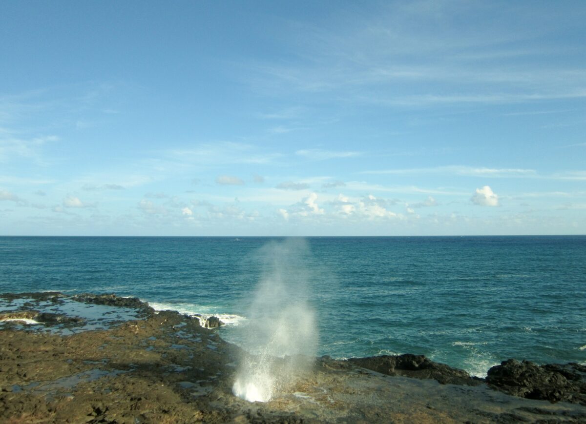 Spray rising from the Spouting Horn blowhole over teal water