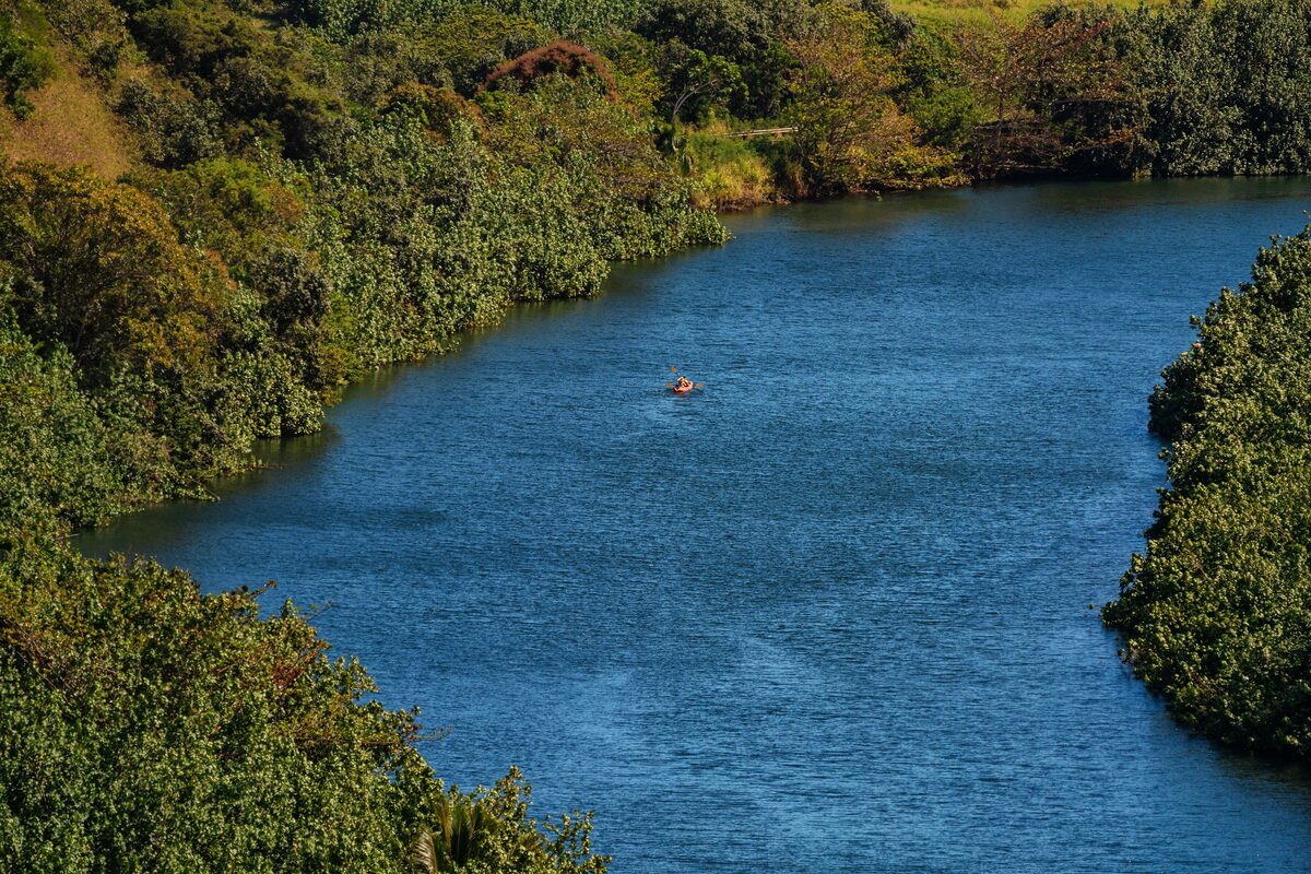 Wailua River winding blue between green banks, with a kayak