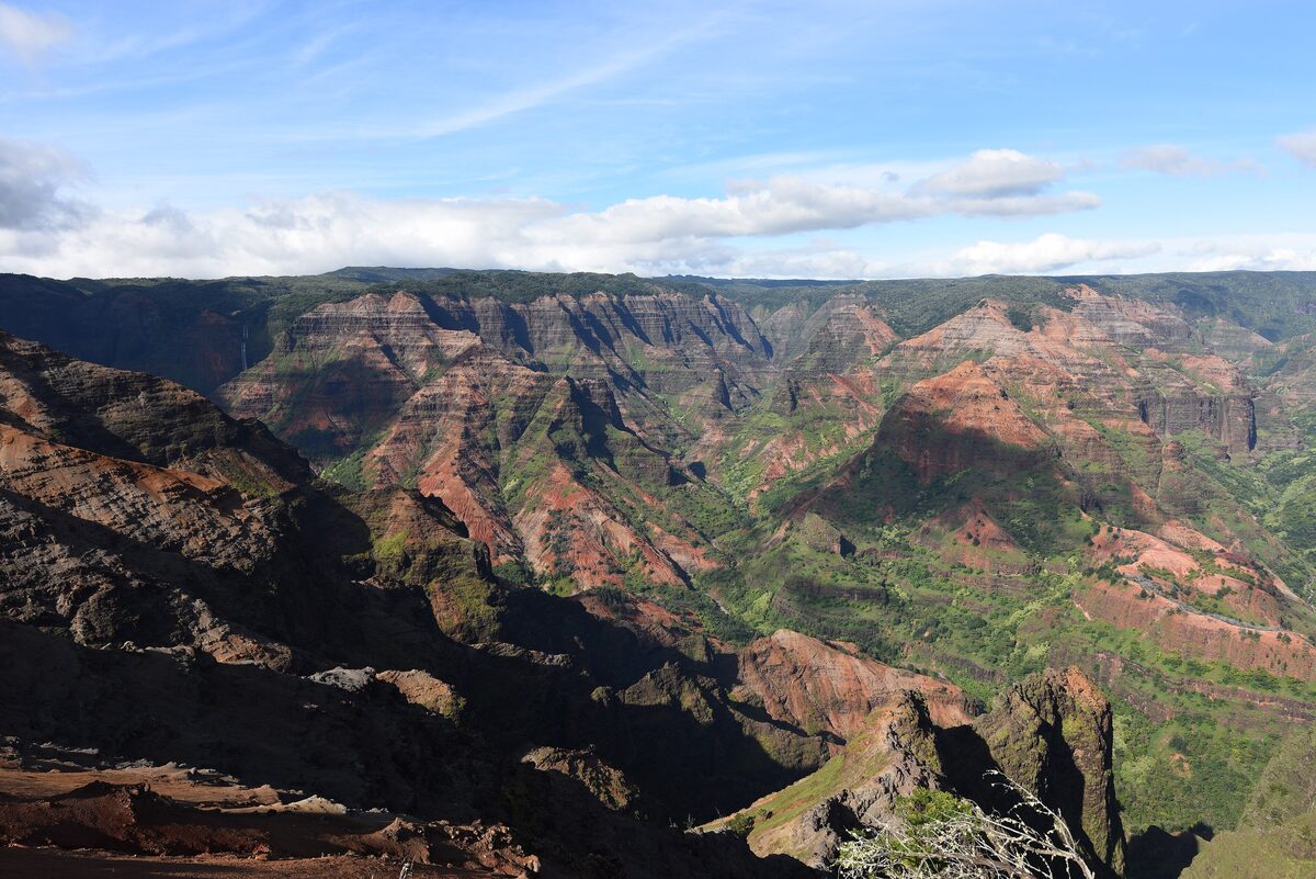 Red and green layered cliffs of Waimea Canyon under blue sky