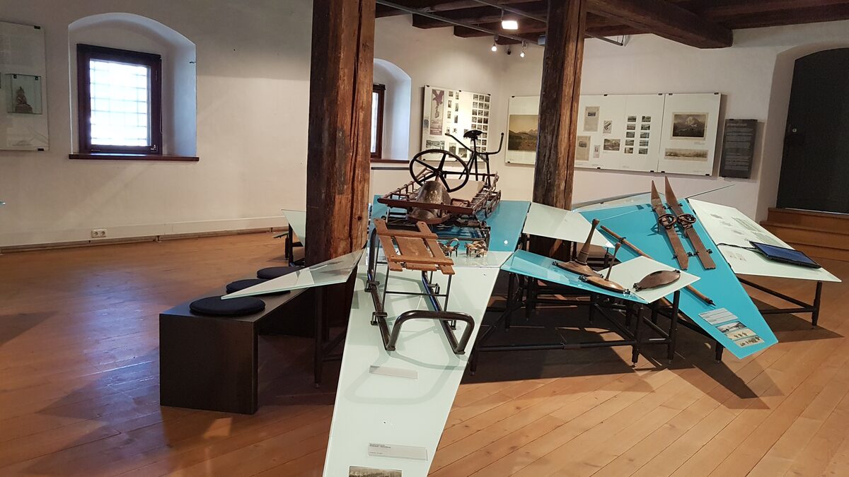 Historic skis and sleds on display in a wood-beamed room of the Museum Kitzbühel
