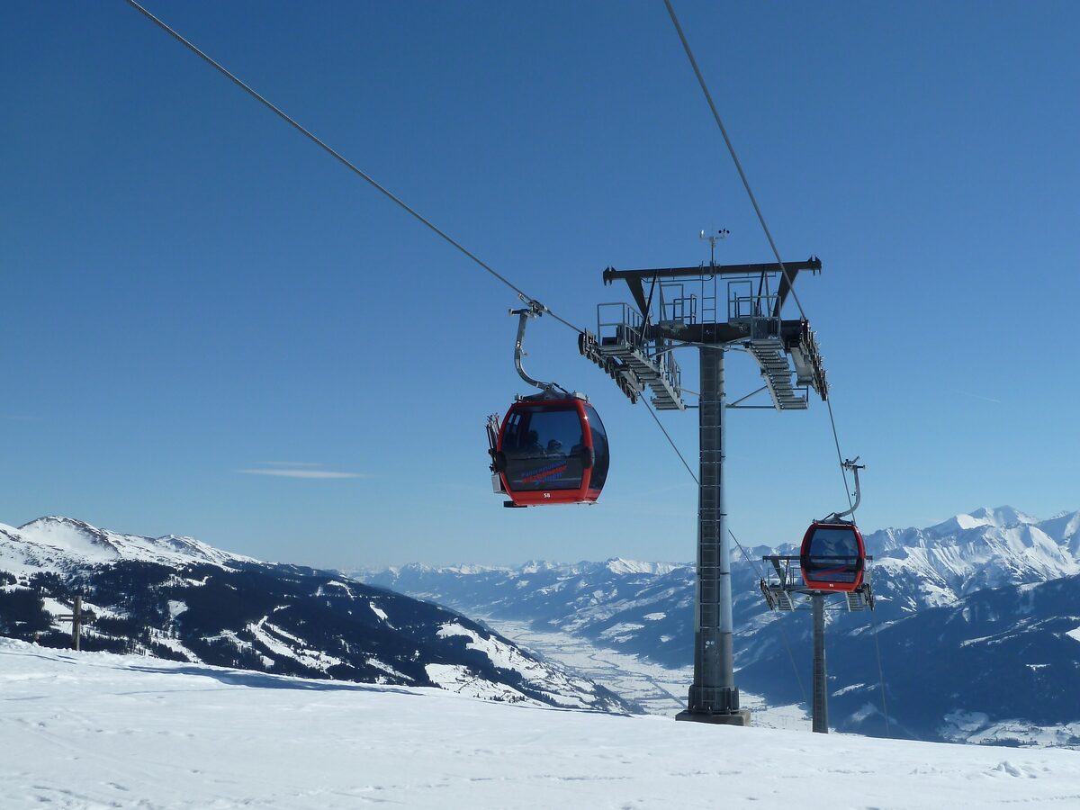 A Panoramabahn gondola above sunny snow slopes, with the Salzach valley and high mountains behind