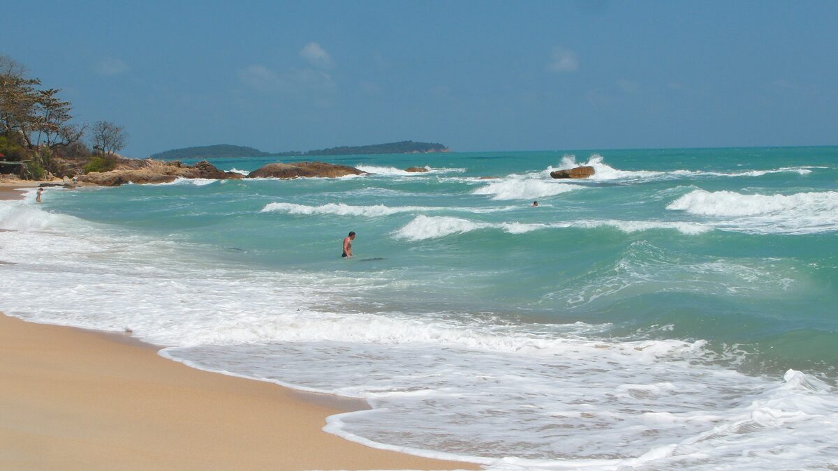 Waves breaking on sand at Chaweng Noi, the northern end of Chaweng beach, with rocks at the shore