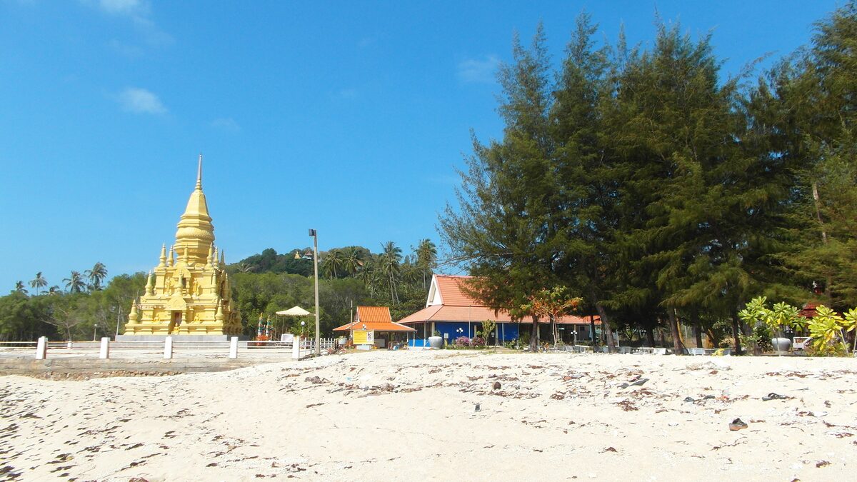 The golden pagoda of Laem Sor on a sandy beach under a blue sky