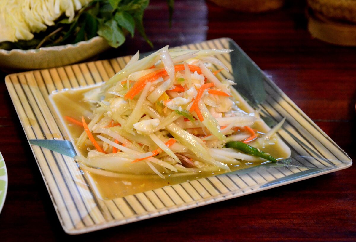 Shredded green papaya salad with carrot on a striped plate