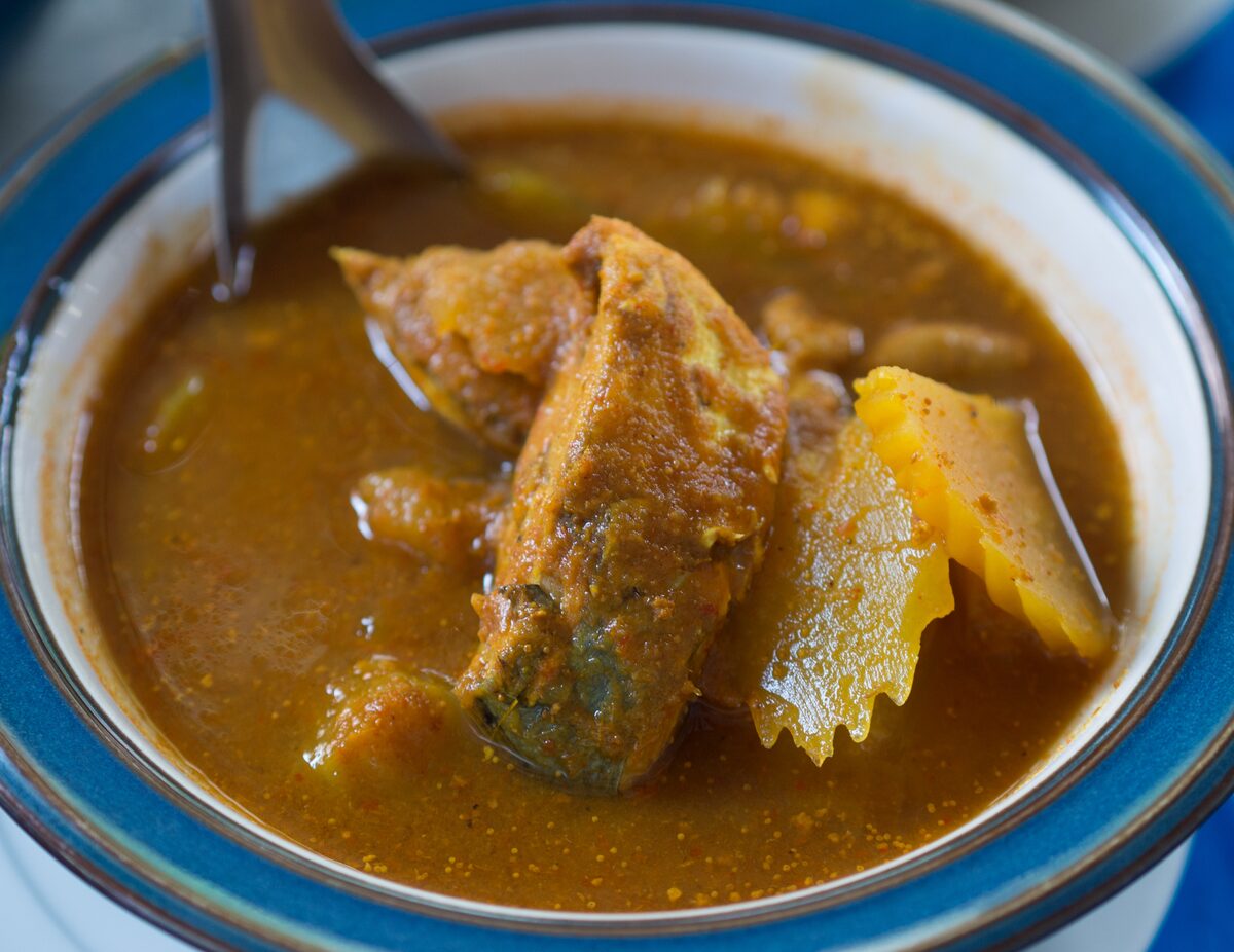 Southern sour fish curry in an orange-brown broth, served in a blue-rimmed bowl
