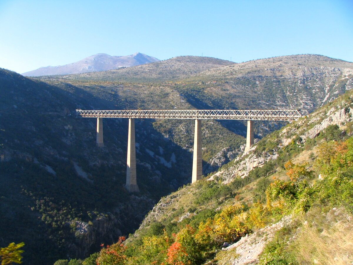 The Mala Rijeka viaduct: a steel railway bridge on tall piers high above the canyon, with forested hills around it