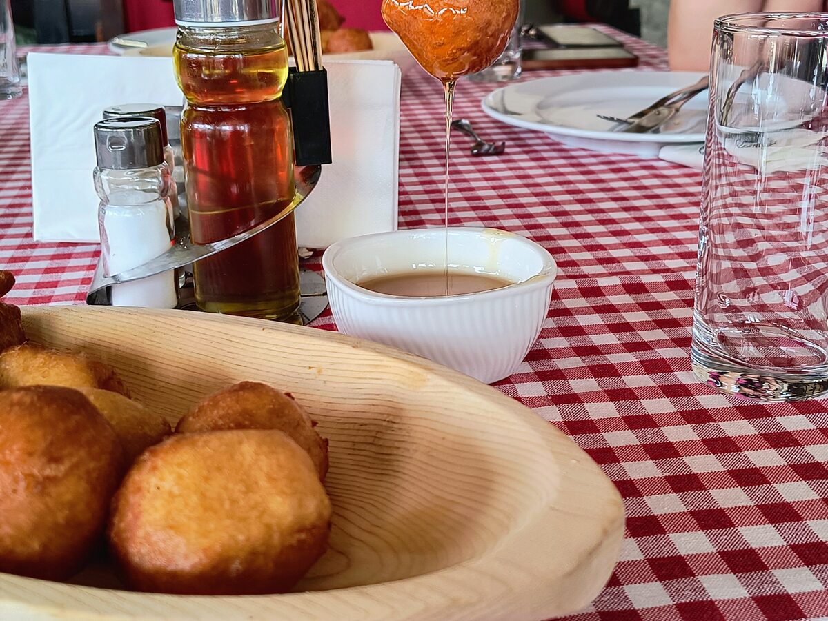 Priganice: small fried dough balls in a wooden bowl on a red-checked tablecloth