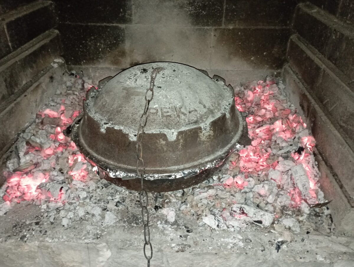 A cast-iron bell lid, a sač (called peka in Croatia), sitting in a hearth on glowing embers
