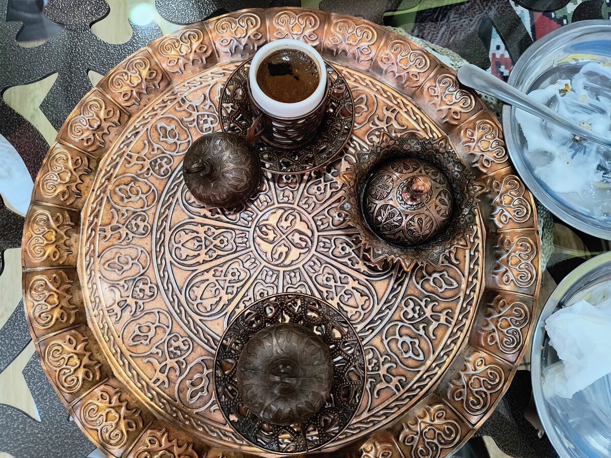 A small cup of strong Serbian coffee on a copper serving tray with lidded sugar bowls