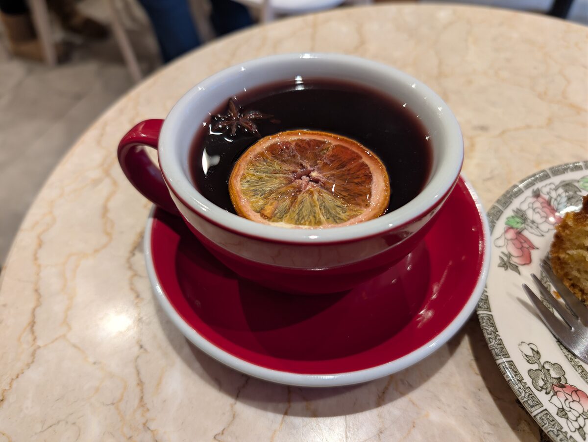 A cup of mulled wine with a dried orange slice and a star anise on a marble table