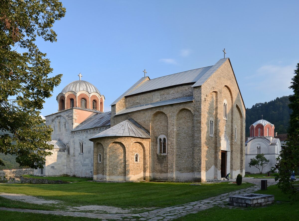 The medieval stone and marble churches of Studenica Monastery, with a red-tiled dome and a green lawn in front