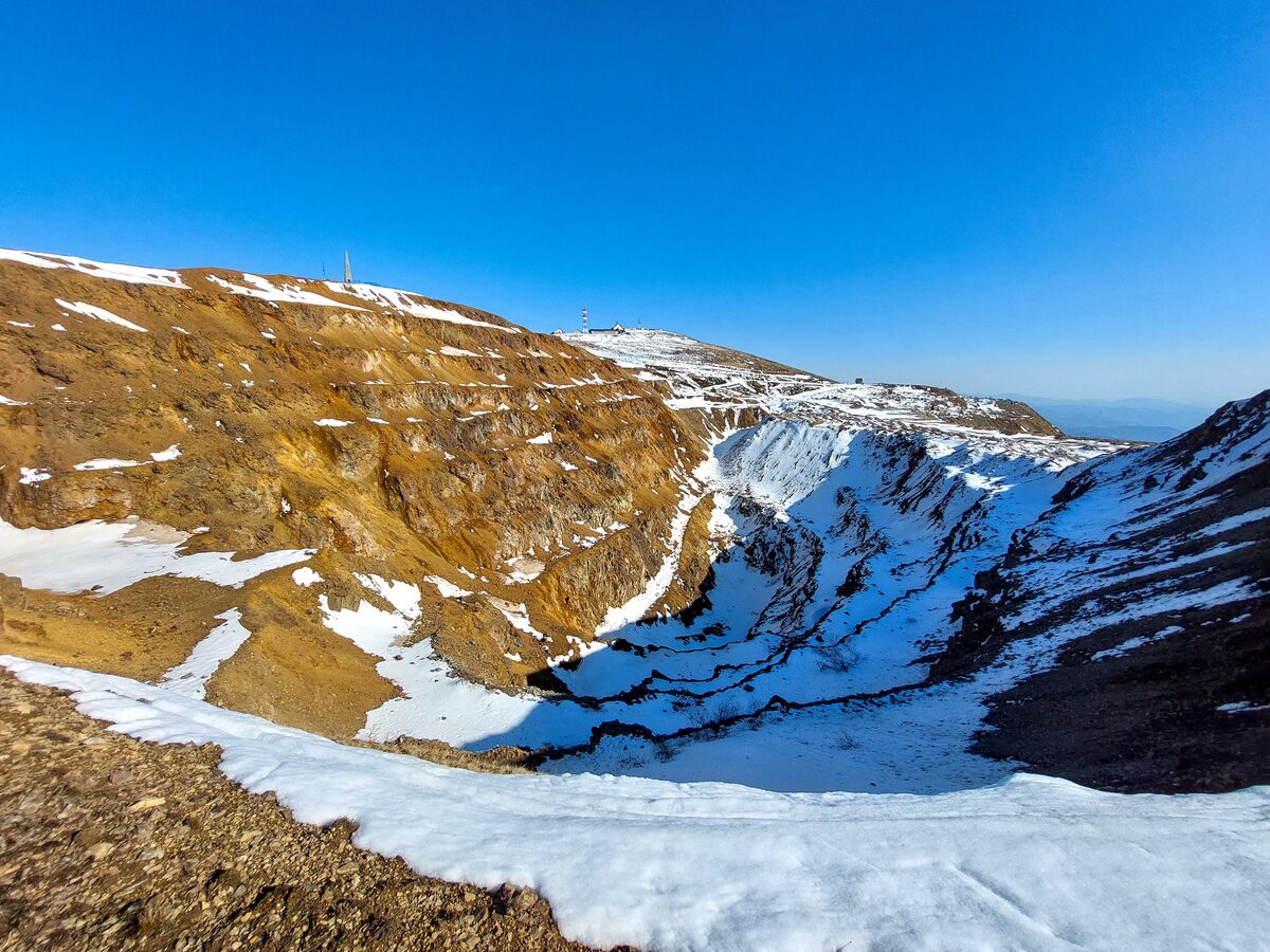 The old open-pit mine on Suvo Rudište, with snow in the gullies and the summit buildings on the ridge above