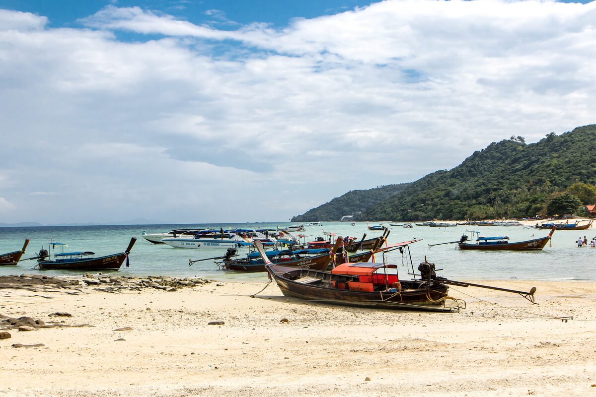 Longtail boats lying on the sand and in the shallows of Ao Nang beach at low tide