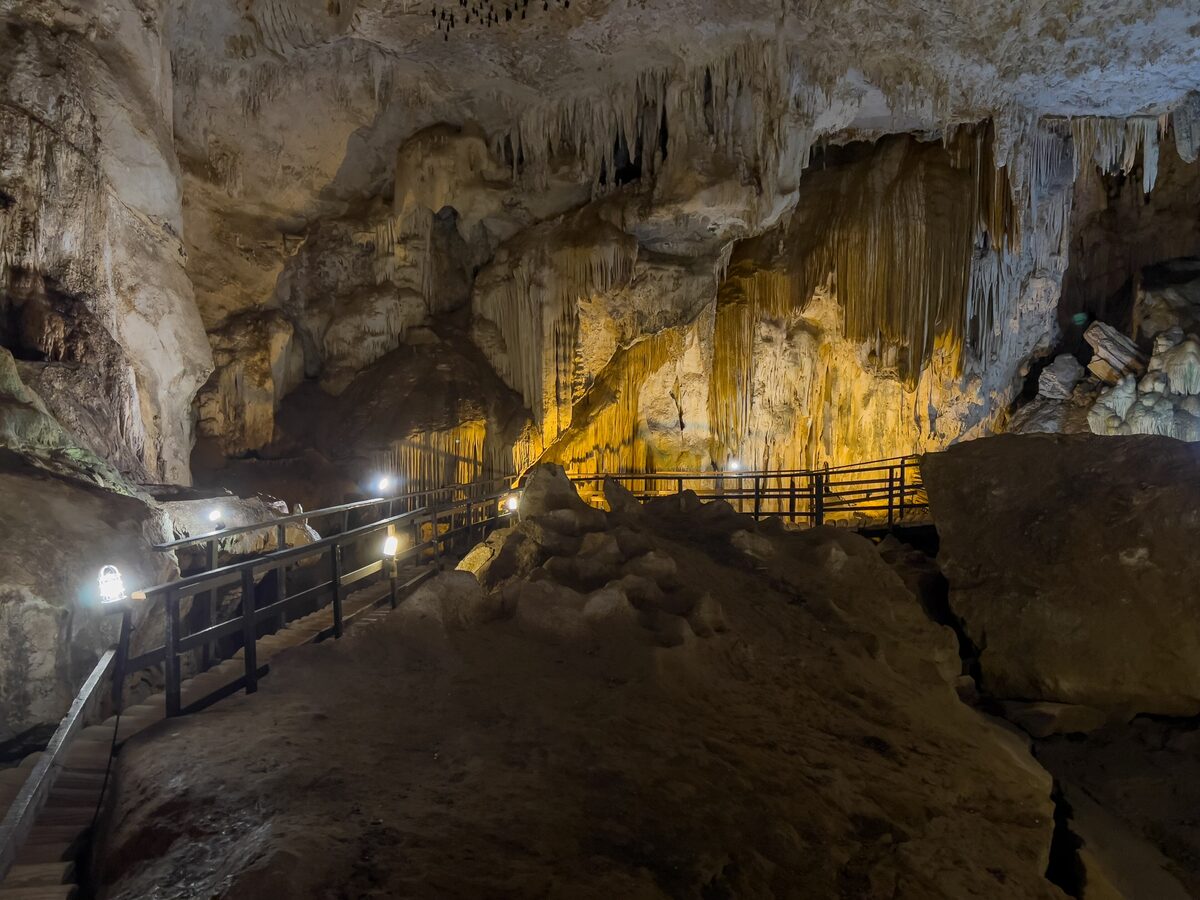 Stalactites lit by spotlights above a wooden walkway inside Diamond Cave on Railay