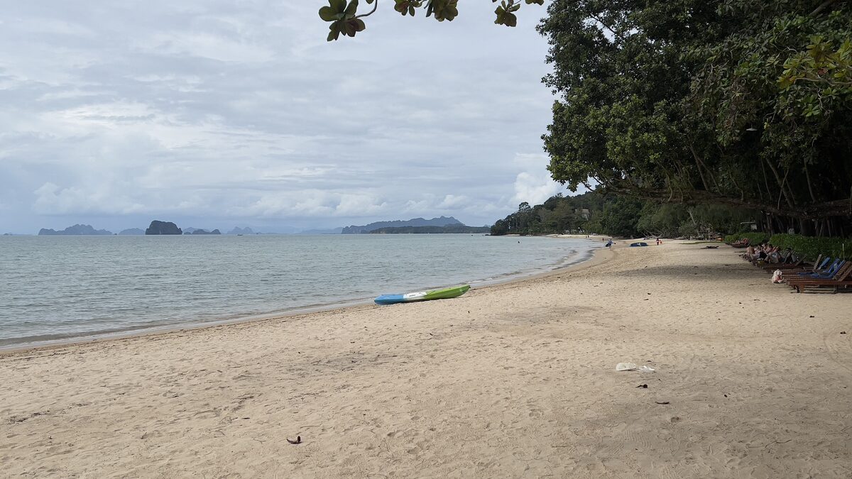Sand beach at Tubkaek on the Klong Muang coast, with a few rocky islands on the horizon under a cloudy sky