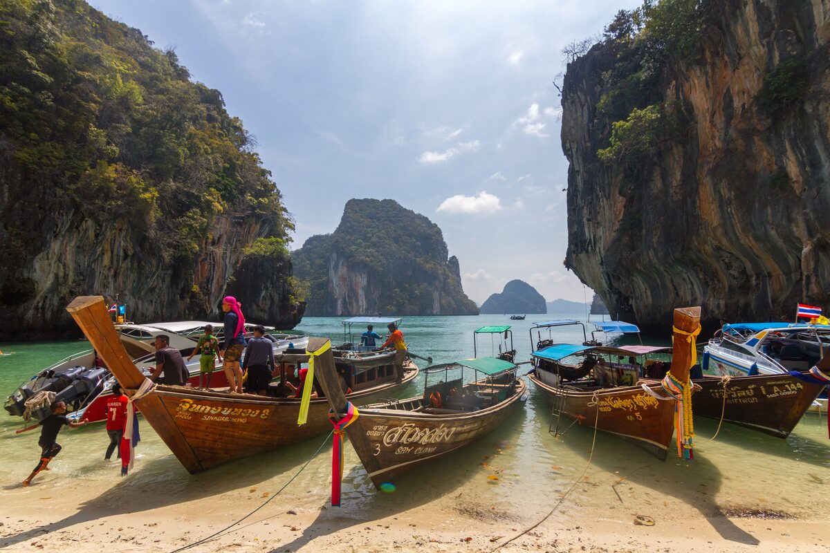 Longtail boats nosed onto the sand at Ko Lao Lading between two limestone cliffs