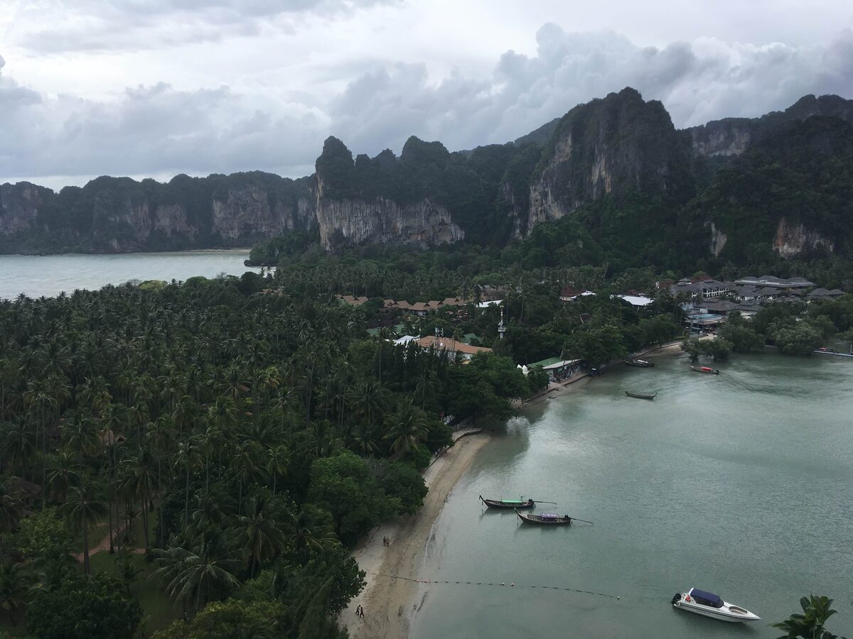 Aerial view of Railay Beach from the viewpoint, with palms and boats in the bay below the cliffs