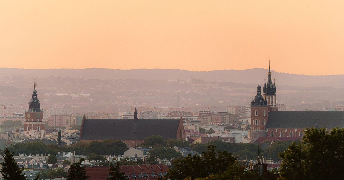 Kraków's Old Town skyline at sunset, with the Town Hall Tower on the left and the two towers of St. Mary's Basilica on the right