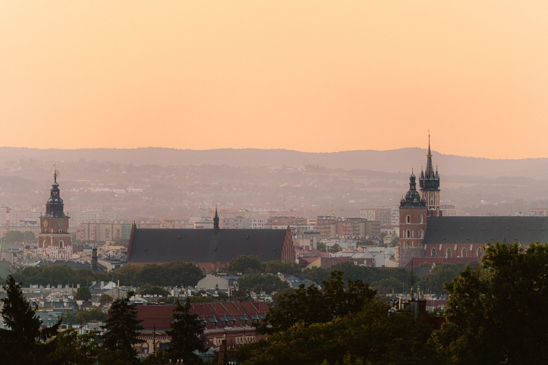 Kraków's Old Town skyline at sunset, with the Town Hall Tower on the left and the two towers of St. Mary's Basilica on the right