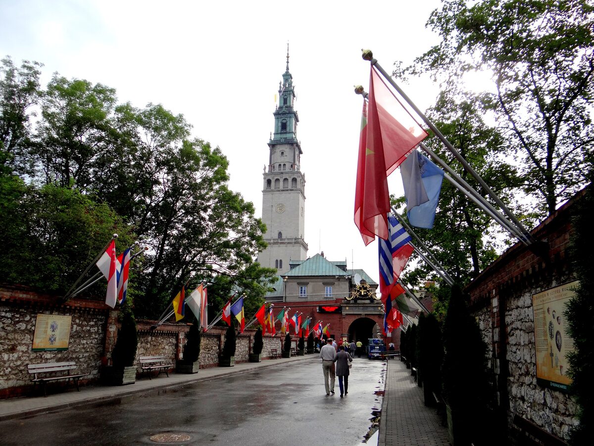 The avenue to Jasna Góra monastery lined with flags, with the monastery tower rising behind the gate