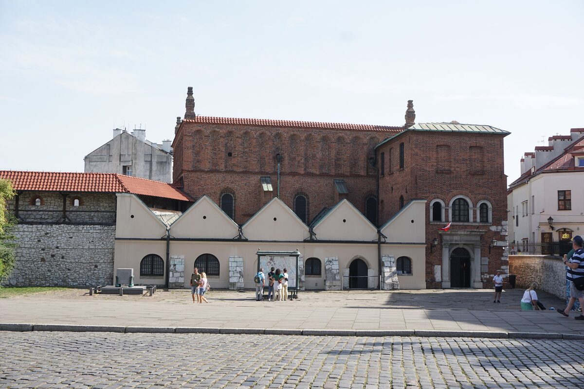 The brick Old Synagogue on Szeroka Street in Kazimierz, behind a low wall with a row of pointed gables