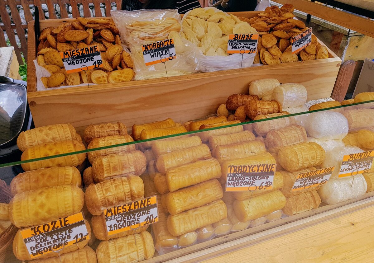 Rows of smoked oscypek sheep's cheeses with carved patterns on a market stall