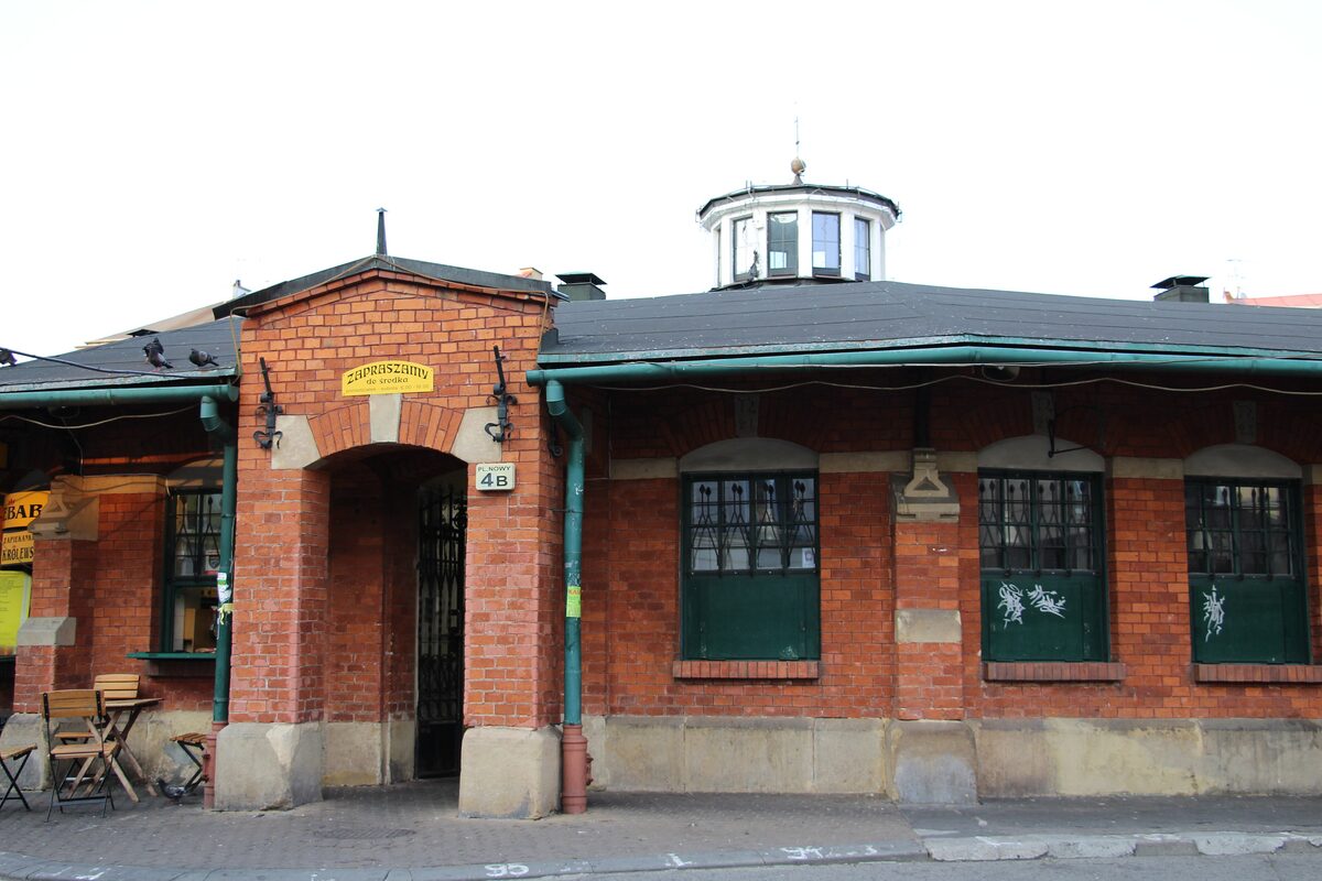 The round brick market hall on Plac Nowy with a zapiekanka window under a yellow sign