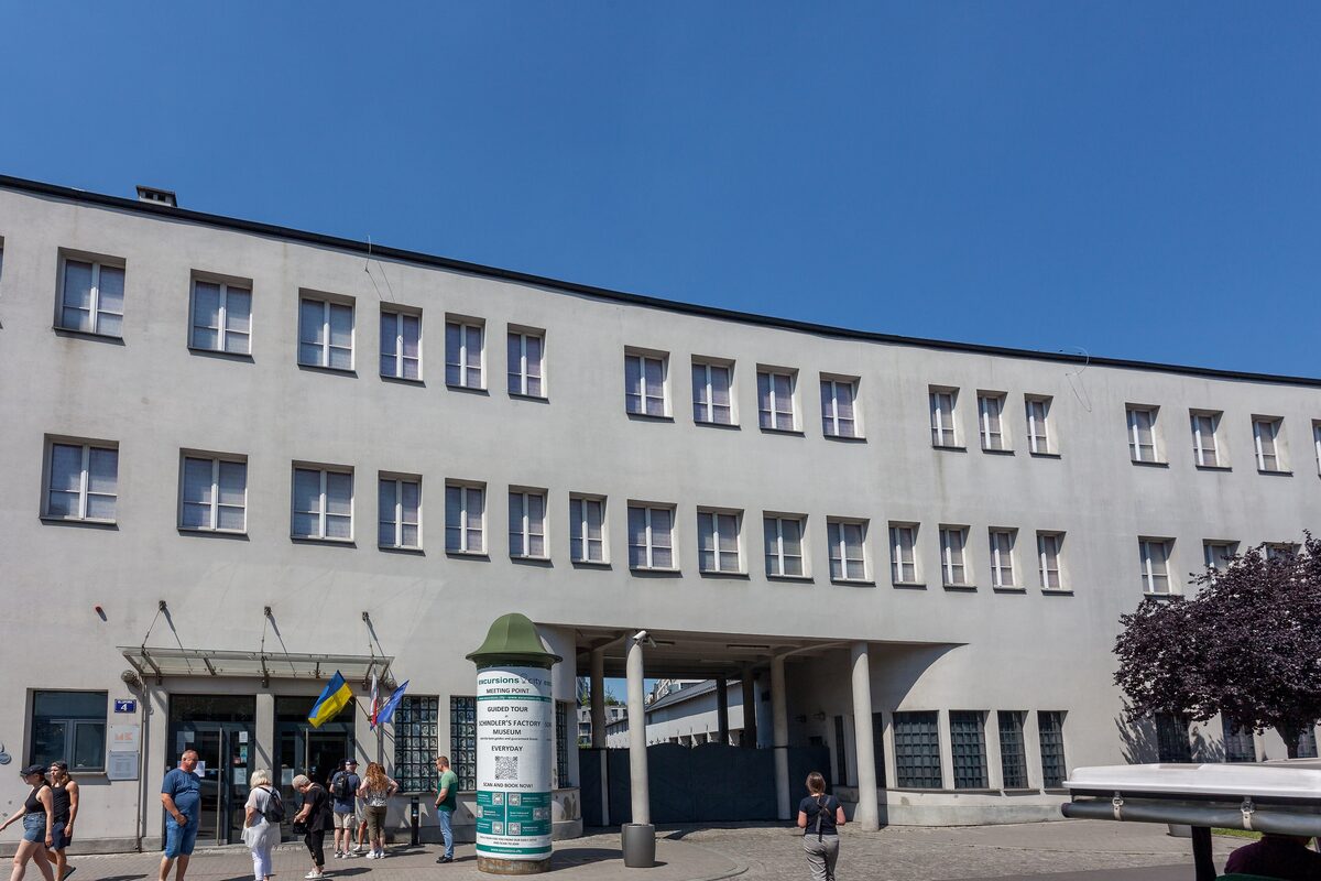 The long white facade of Oskar Schindler's former enamel factory on Lipowa Street, with visitors at the entrance