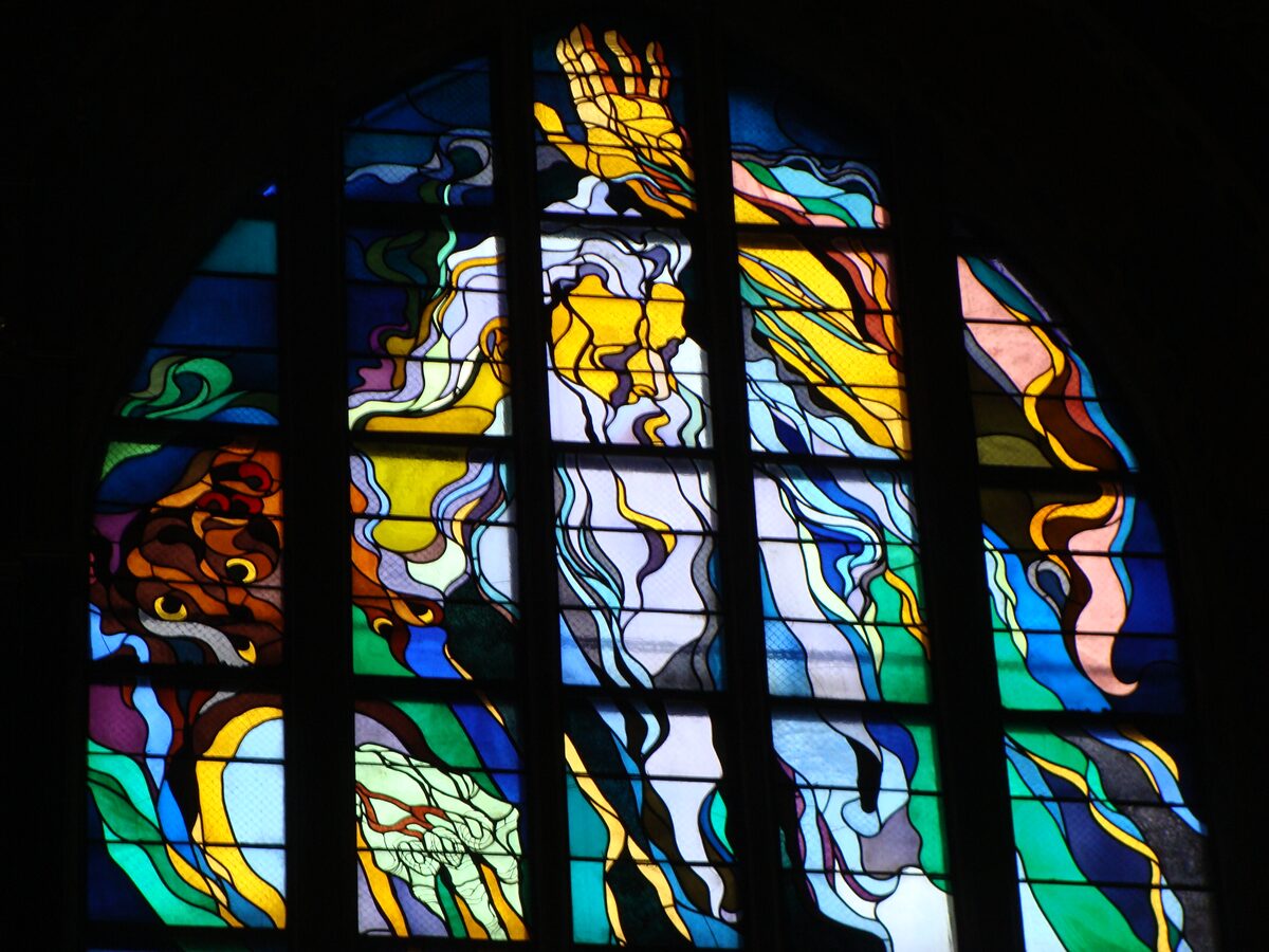 Detail of Wyspiański's stained glass window God the Father in the Franciscan Basilica, a white-bearded figure in swirling yellow, blue and green glass