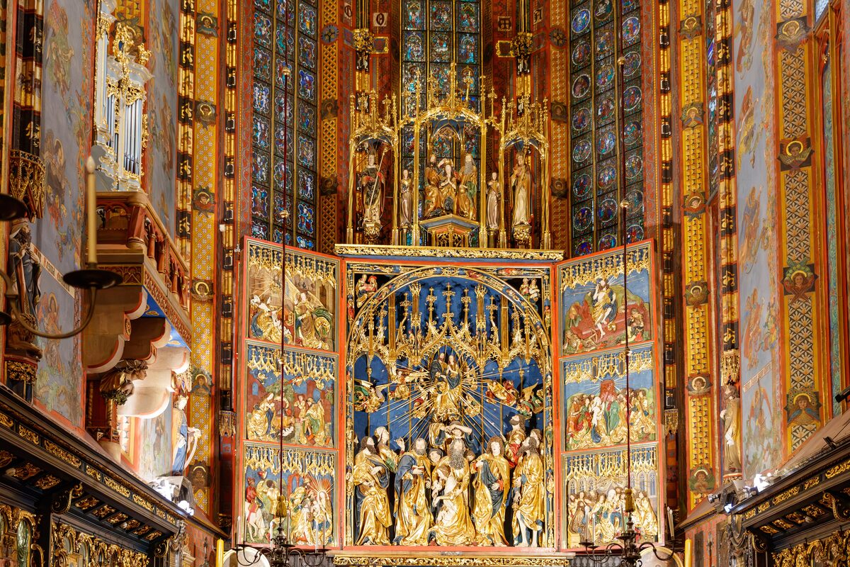 The gilded Veit Stoss altarpiece in St. Mary's Basilica with its wings open, under painted Gothic walls and stained glass