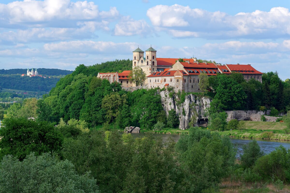 Tyniec Abbey on its white limestone cliff above the Vistula, surrounded by green trees