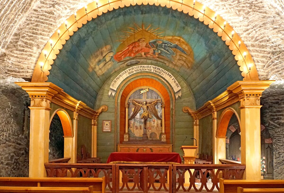 An underground chapel in the Wieliczka salt mine, with a crucifix, painted vault and pews, all carved inside the rock salt