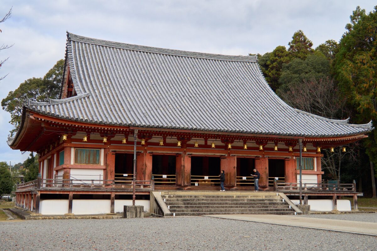 The red wooden hall of Daigo-ji with its grey tiled roof above a gravel courtyard