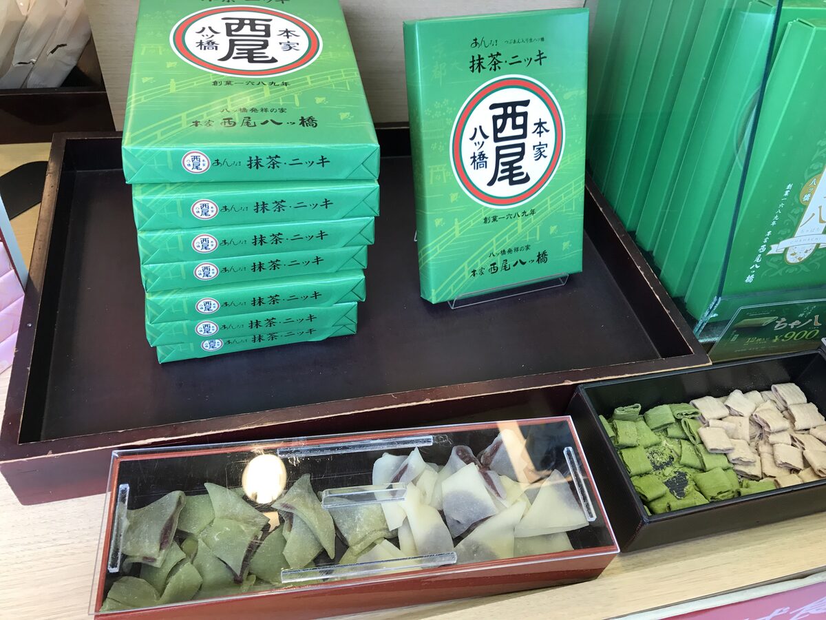 Green boxes of matcha yatsuhashi, with a tray of the triangular sweets