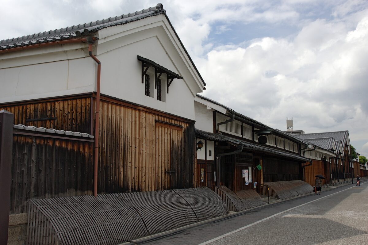 A street of white-walled sake warehouses and wooden brewery buildings in Fushimi