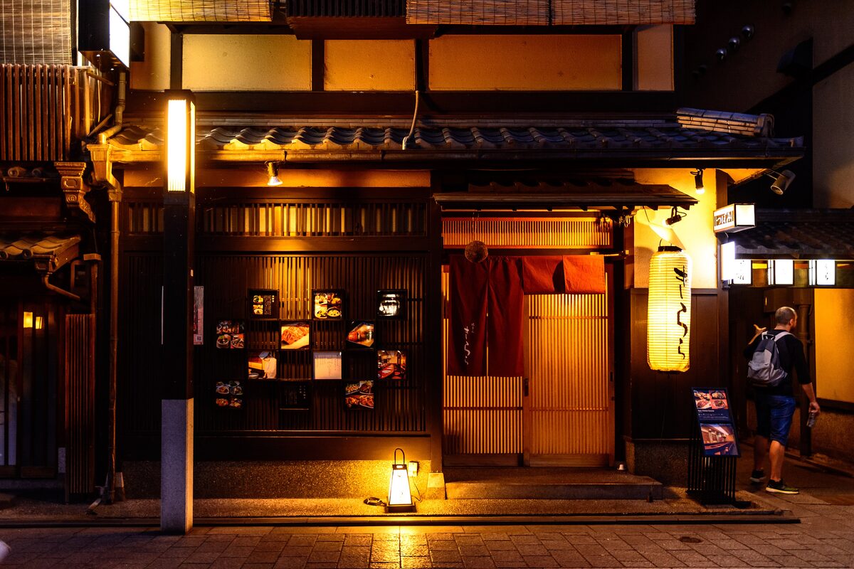 Lantern-lit wooden house fronts on a Gion lane in the evening