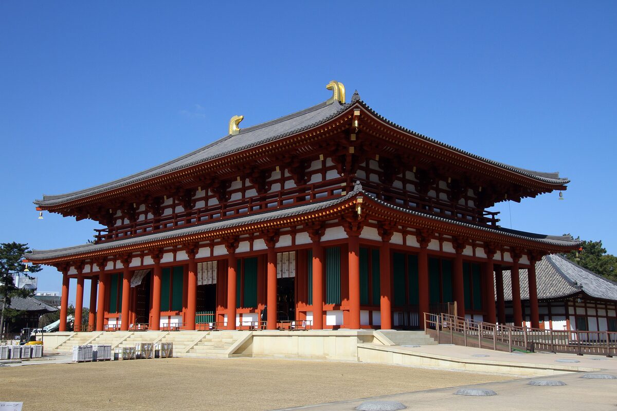The Central Golden Hall of Kofuku-ji, a vermilion two-roofed hall with gold ridge ornaments, under a deep blue sky