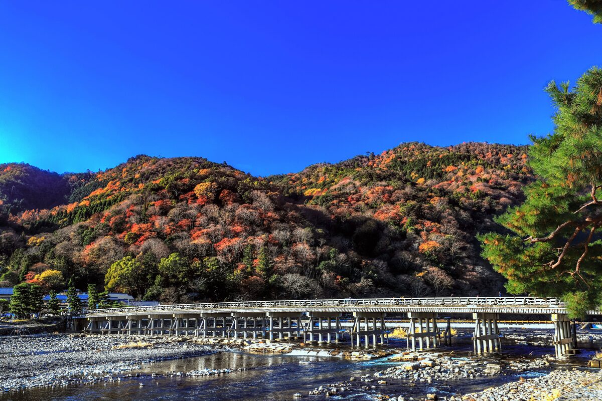Togetsukyo bridge over the Katsura River, with the hills of Arashiyama red and orange in autumn