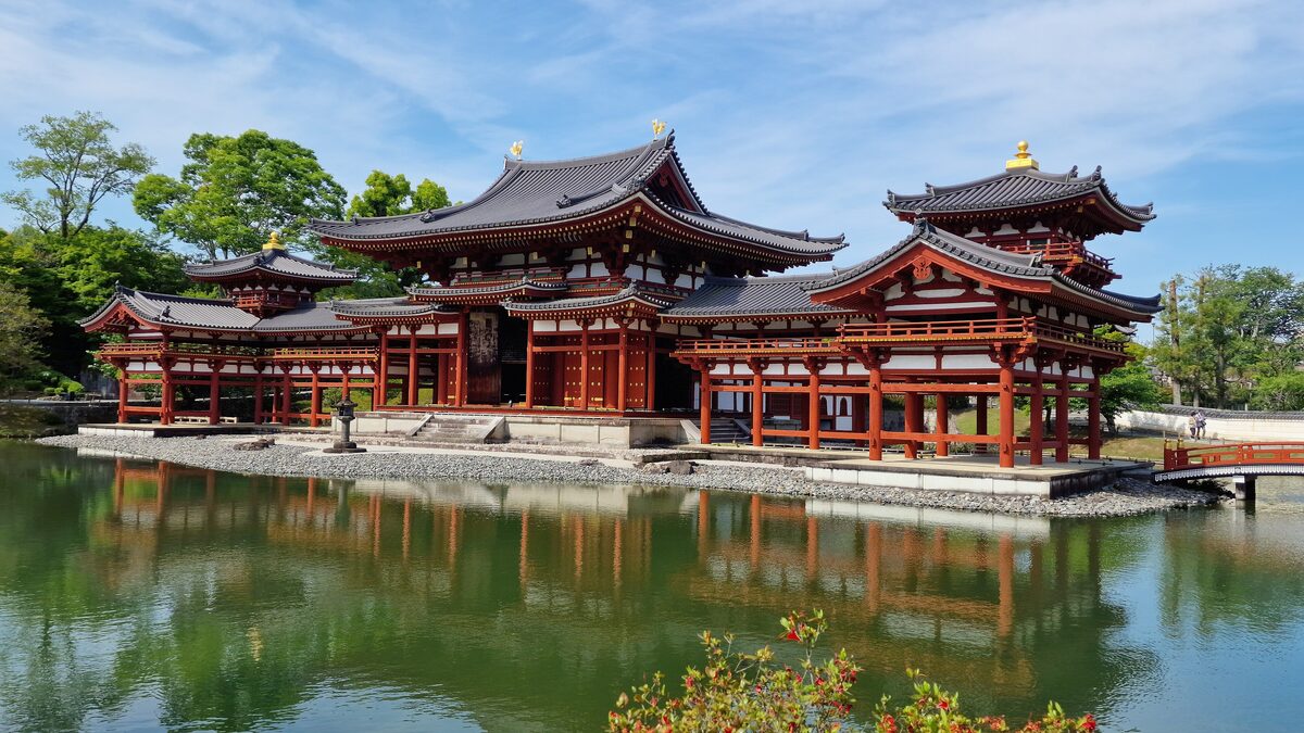 The vermilion Phoenix Hall of Byodo-in in Uji, with its wings and tail corridor reflected in the green pond in front