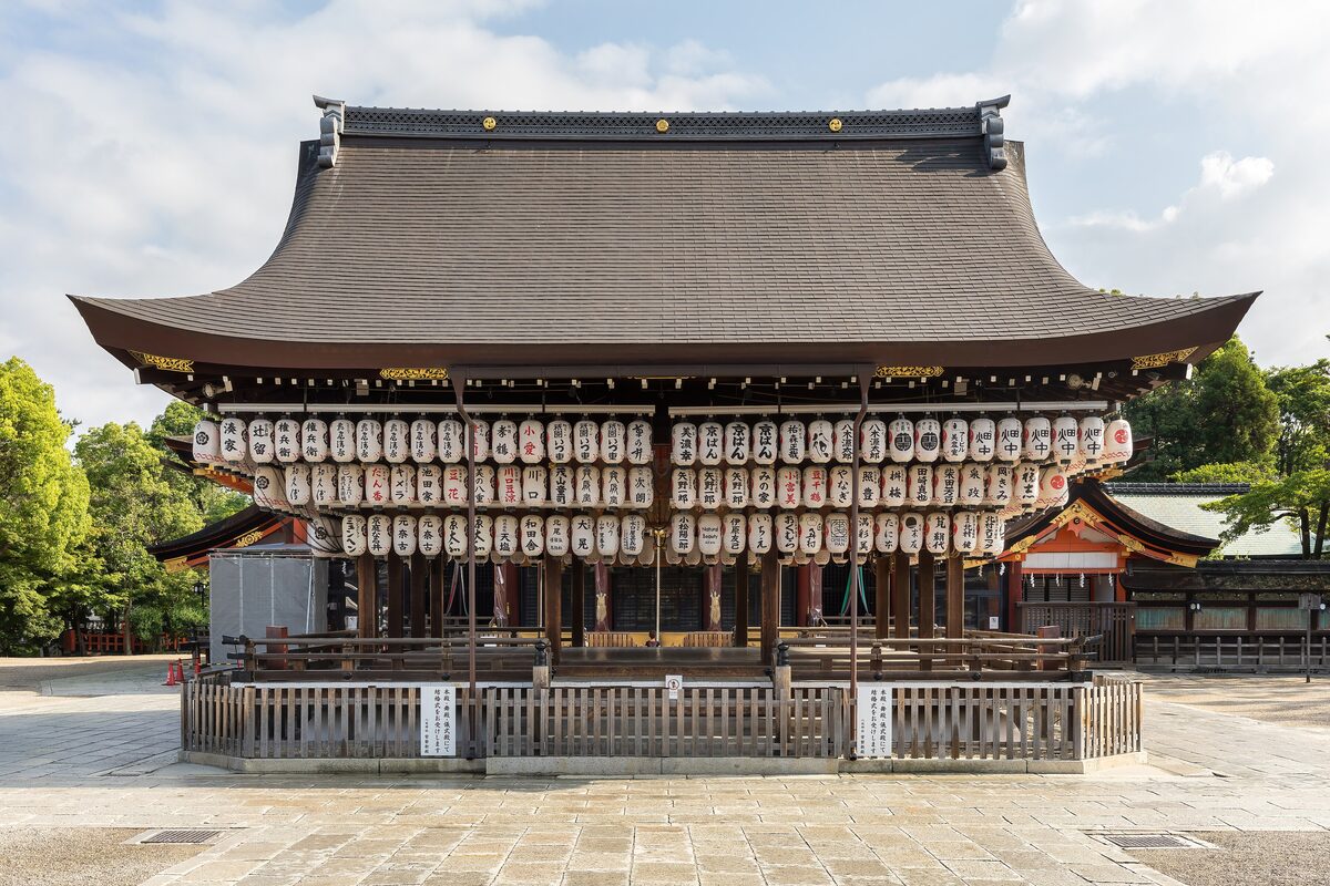 The dance stage of Yasaka Shrine seen from the front, under a great curved roof and hung with rows of white paper lanterns
